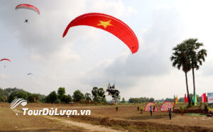 Paramotor performance with a parachute bearing the Vietnamese national flag flying over the Tri Ton sky during the opening ceremony of the Ho Chi Minh City Open Paragliding Tournament 2025.