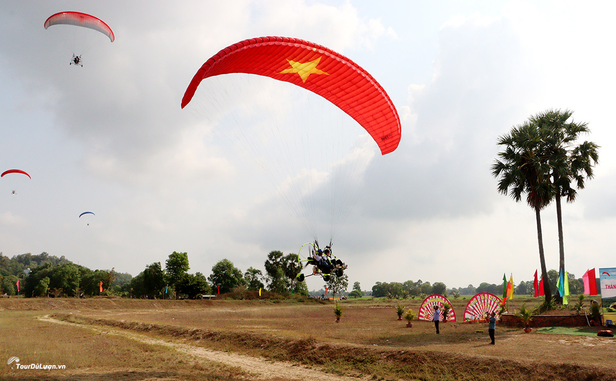 Paramotor performance with a parachute bearing the Vietnamese national flag flying over the Tri Ton sky during the opening ceremony of the Ho Chi Minh City Open Paragliding Tournament 2025.